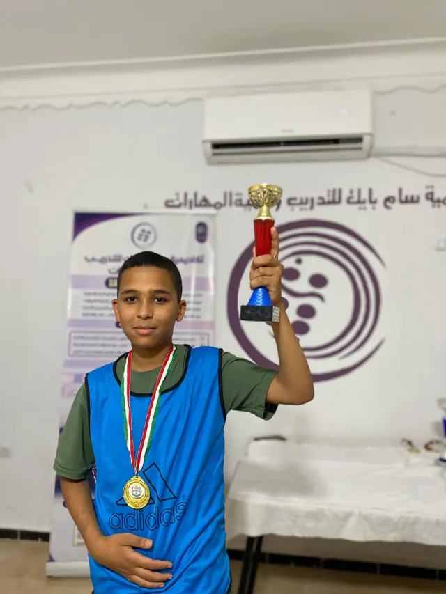 طفل يحمل كأسًا وميدالية