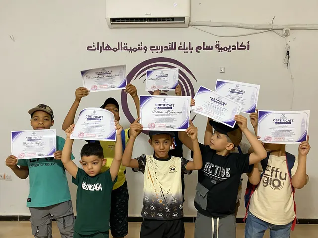 أطفال يرفعون شهادات ختام مخيم اللغة الإنجليزية