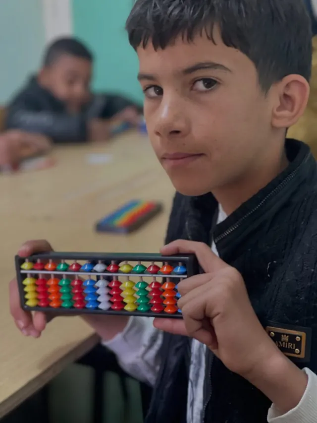 طفل يحمل أداة السوروبان الملونة